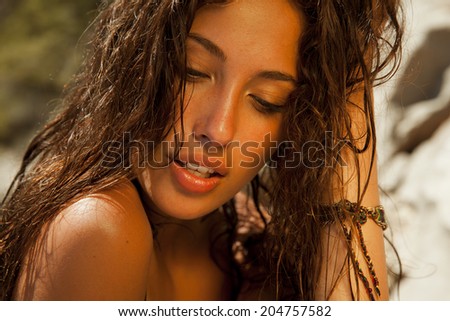 beauty portrait of attractive brunette with golden tan and wet hair. Toned in warm colors. horizontal shot by the sea.