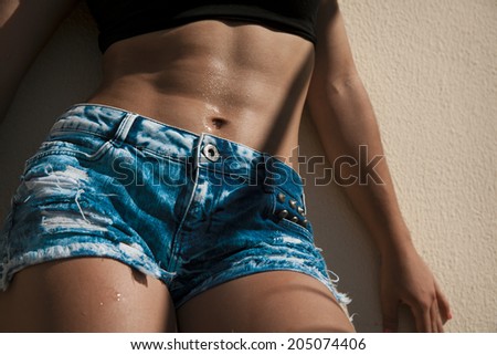 Beautiful woman body in denim jeans shorts . Toned in warm colors.
