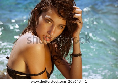 Carefree beautiful brunette with wet look & long hair on the beach. Natural woman beauty. Toned in warm colors. Copy space for your text. horizontal shot, outdoors