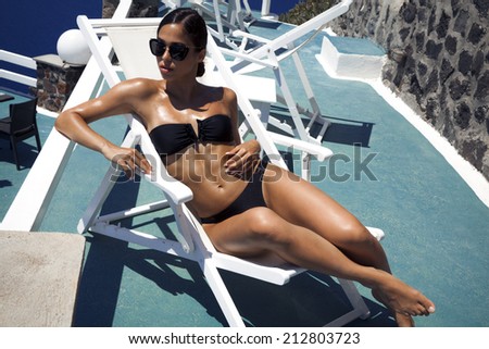 Fashion girl in beautiful bikini lying near swimming pool. Vacations And Tourism Concept. Tropical Resort.