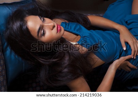 Closeup fashion portrait of young sexy woman relaxed on comfortable luxury sofa. Blue Princess. Indoor, studio shot. toned in warm colors. horizontal shot
