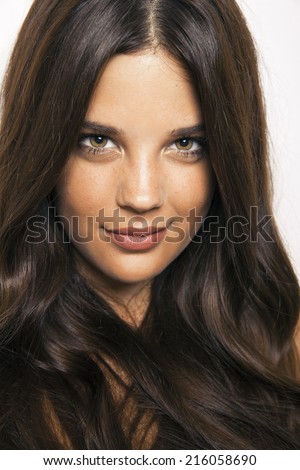 Caucasian brunette model with long wavy hair and perfect light skin. Toned in warm colors, Cosmetics concept, vertical shot, studio