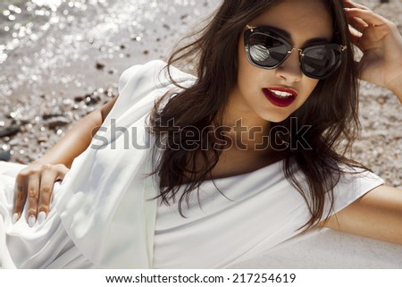 beautiful stylish female in white dress sitting in a boat.Horizontal summer shot. Toned in a warm colours..
