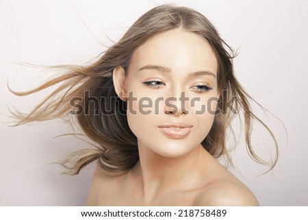 Caucasian blonde model with long wavy hair in the air and perfect light skin. Toned in warm colors, Cosmetics concept, Horizontal shot, studio