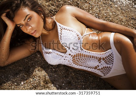 fashion outdoor photo of sexy beautiful woman with long hair in elegant white bikini with accessories relaxing on summer beach. horizontal shot