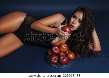 Sexy beautiful girl lying on floor with red apple in the hand. Attractive and wet beauty. Studio shot. Horizontal