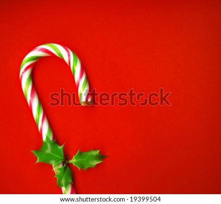 Candy cane with pretty holly leaves on red background, candy cane