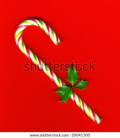 Candy cane with pretty holly leaves on red background, candy cane