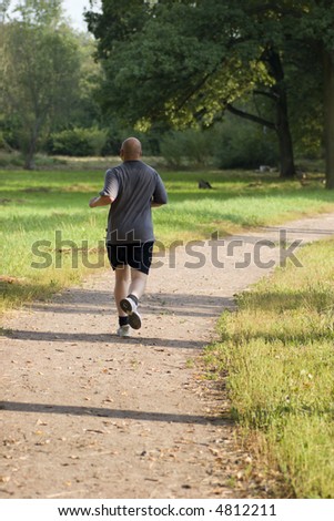 Bold muscular wet man jogging in the park in sunset lights