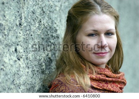 Portrait of confident sad woman wearing scarf near grey grained wall