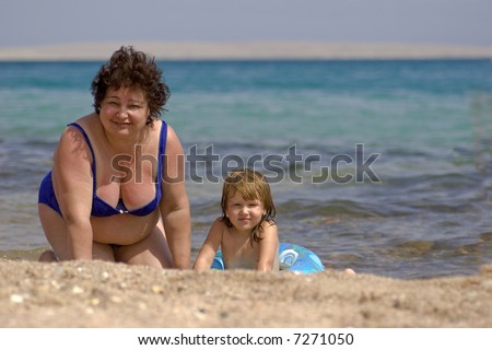 Grandmother and grandchild having fun  in the water on the beach hot sunny day