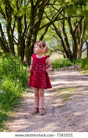 Rural girl wearing red dress and ponytails looking away standing on the road