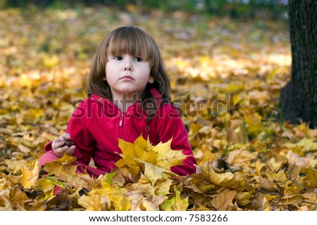 Kid in sitting the maple leaves looking away with sad face