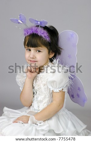 Little girl wearing fairy costume with wings looking at you with sad smile