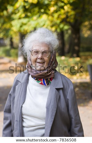 Outdoors autumn portrait of cheerful old lady with grey hair and scarf
