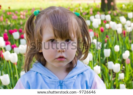 Portrait of little girl with curious face over white and red tulips background