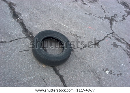 Thrashed old tire lying on asphalt grey background