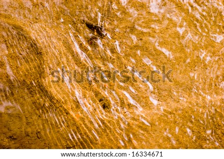 Golden sand under transparent flowing water background abstraction