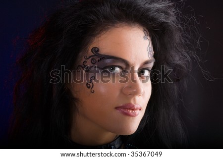 stock photo Beautiful woman wearing tribal makeup over dark background