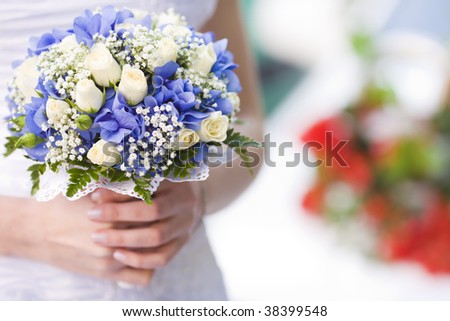 Bride holding blue and beige flowers bouquet in hands