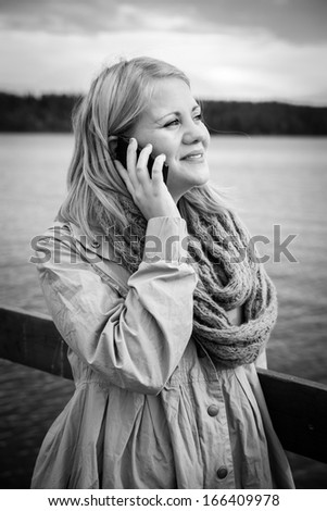 black and white image of a woman talking on the phone in a natural setting