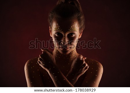 studio portrait of beautiful female woman with futuristic cristal makeup looking up