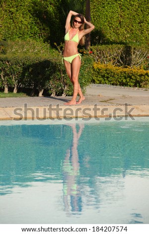 Sexy girl in yellow bikini posing near swimming pool