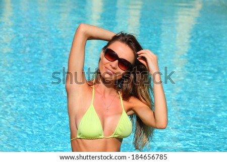 Sexy girl in yellow bikini posing near swimming pool