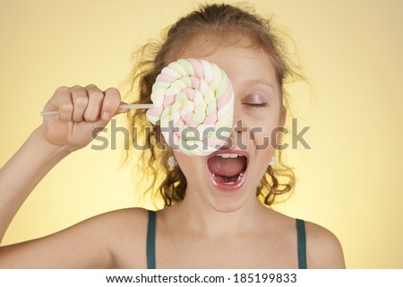 Funny child with candy, happy little girl eating big sugar lollipop, kid eat sweets. surprised child with candy. isolated on white background, studio.