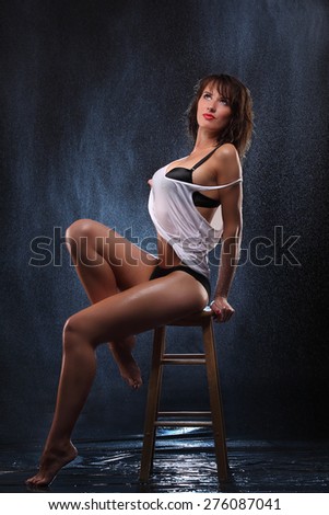 Young sexy woman wet sitting on chair. Water studio photo. fresh