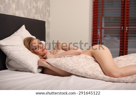 Fashionable photo sleeping nude woman in a bedroom studio