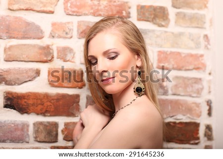 young beautiful girl posing nude against a brick wall studio