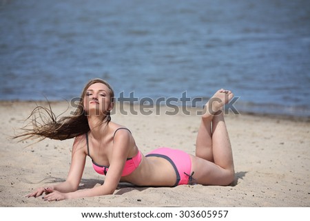 Beautiful young woman in bikini on the sunny beach outdoor