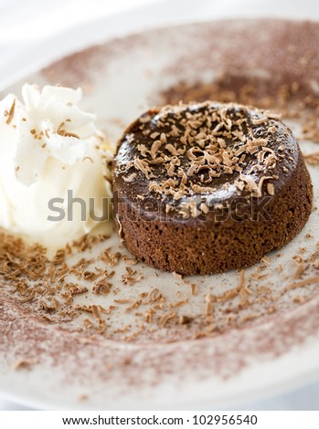 Chocolate souffle on plate with whipped cream and chocolate flakes