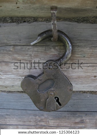 Hanging loop on old metal padlock against the background of timbered wall