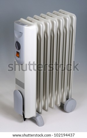 An oil filled radiator with wheels against a gray background.