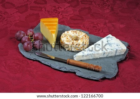 Selection of cheeses on a Welsh slate cheese board comprising of Smoked Irish Cheddar, Danish soft cheese coated with pineapple and almonds and Gorgonzola.