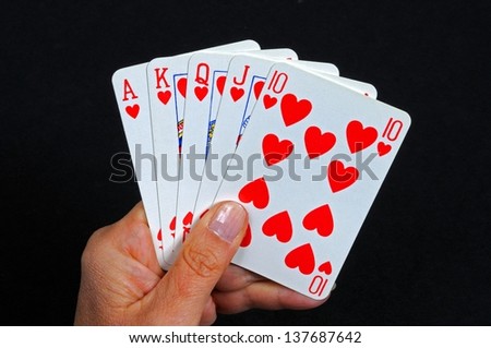 Royal flush poker hand in the heart suit against a black background.