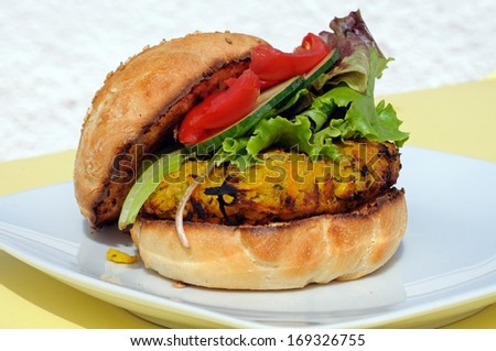 Vegetarian chickpea, sweetcorn and carrot burger with salad in a sesame seed bun, UK.