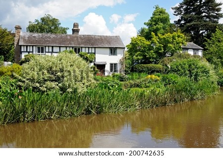 EARDISLAND, UNITED KINGDOM - JUNE 5, 2014 - River Arrow with a pretty black and white timbered cottage to the rear, Eardisland, Herefordshire, England, UK, June 5, 2014.