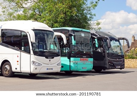 BOURTON ON THE WATER, UK - JUNE 12, 2014 - Three tourist coaches parked in a row in a coach and car park, Bourton on the Water, Gloucestershire, England, UK, Western Europe, June 12, 2014.