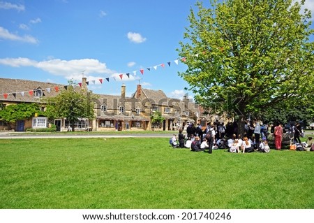 BROADWAY, UK - JUNE 12, 2014 - Group of school children on the village green and shops along High Street in the centre of the village, Broadway, Cotswolds, Worcestershire, England, UK, June 12, 2014.