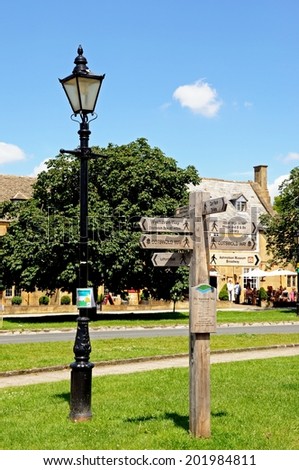 BROADWAY, UK - JUNE 12, 2014 - Traditional wooden signpost on the village green along the High Street giving directions to various walks, Broadway, Cotswolds, Worcestershire, England, June 12, 2014.