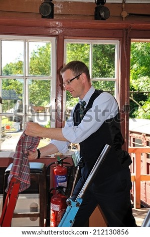 Highley, UK - July 10, 2014 - Signalman operating the Main Line lever on the mechanical lever frame inside the signal box at the railway station, Highley, Worcestershire, England, UK, July 10, 2014.