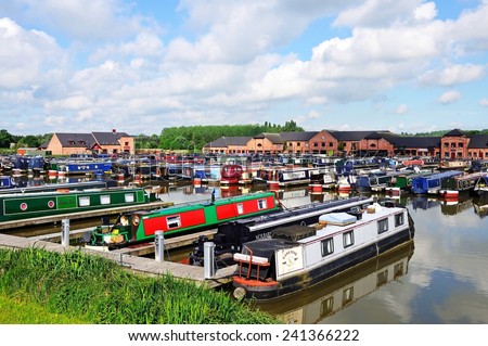 BARTON-UNDER-NEEDWOOD, UK - MAY 21, 2014 - Narrowboats in the canal basin with shops, bars and restaurants to the rear, Barton Marina, Barton-under-Needwood, Staffordshire, England, UK, May 21, 2014.