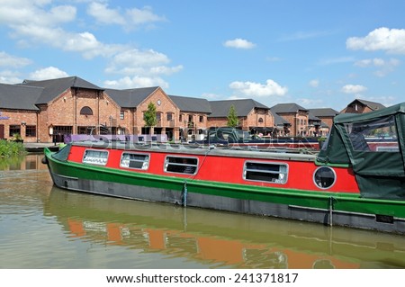 BARTON-UNDER-NEEDWOOD, UK - MAY 21, 2014 - Narrowboats in the canal basin with shops, bars and restaurants to the rear, Barton Marina, Barton-under-Needwood, Staffordshire, England, UK, Western Europe