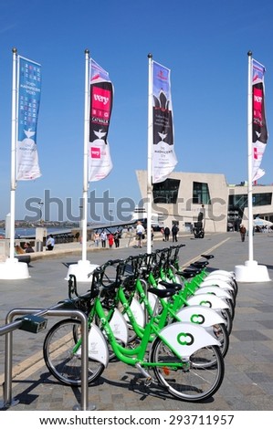 LIVERPOOL, UK - JUNE 11, 2015 - Row of city hire bikes for rent along the waterfront at Pier Head with the Mersey Ferries building to the rear, Liverpool, Merseyside, England, UK, June 11, 2015.