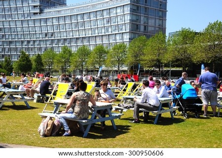 LIVERPOOL, UNITED KINGDOM - JUNE 11, 2015 - People relaxing at picnic benches in Chavasse Park during the Summertime, Liverpool, Merseyside, England, UK, Western Europe, June 11, 2015.