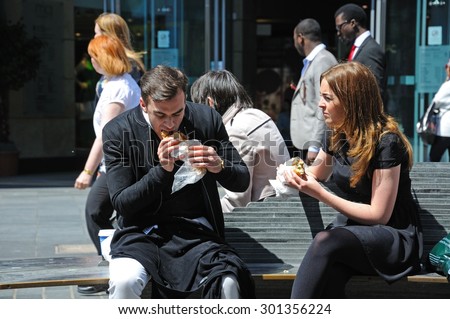 LIVERPOOL, UNITED KINGDOM - JUNE 11, 2015 - Couple sitting on a bench having a takeaway lunch along Whitechapel shoping street in the city centre, Liverpool, Merseyside, England, UK, June 11, 2015.