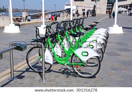 LIVERPOOL, UNITED KINGDOM - JUNE 11, 2015 - Row of city hire bikes for rent along the waterfront at Pier Head with the Mersey Ferries building to the rear, Liverpool, England, UK, June 11, 2015.